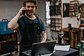 Blacksmith talking on phone in workshop