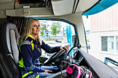 Blond female truck driver driving her vehicle