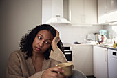 Pensive young woman sitting at home