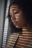 Pensive young woman looking through window