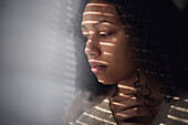 Pensive young woman looking through window