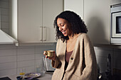 Smiling young woman standing in kitchen