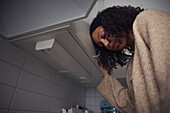 Pensive young woman standing in kitchen