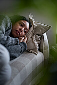 Pensive young woman lying on sofa