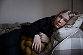 Pensive teenage girl lying on sofa