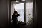 Nachdenkliches Mädchen im Teenageralter blickt durch ein Fenster