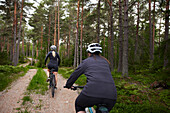 View of women cycling through forest