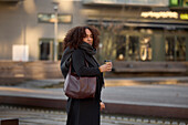 Beautiful woman with takeaway coffee posing on street