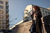 Schöne Frau mit Kaffee zum Mitnehmen und Smartphone auf der Straße