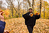 Lächelnde Frau, die Herbstblätter wirft