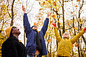 Glückliche junge Freunde, die Herbstblätter werfen
