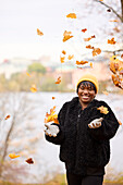 Lächelnde junge Frau, die Herbstblätter wirft