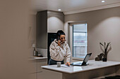 Woman in kitchen talking via cell phone