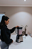 Woman using blender in kitchen