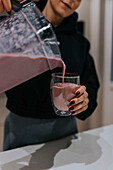 Woman pouring smoothie in glass