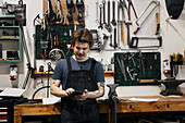 Schmied benutzt Smartphone in seiner Werkstatt