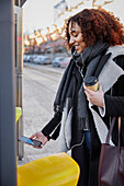 Woman at ticket machine using cell phone to pay