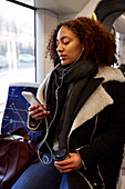 Young woman using cell phone in train