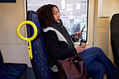 Young woman using cell phone in bus