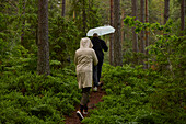 Rear view of people walking through forest