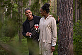 Lächelndes Paar mit Weingläsern im Wald