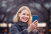 Lächelnde junge Frau beim Telefonieren im Freien