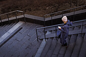 Young woman walking down stairs and using phone