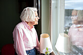 Ältere Frau schaut durch das Fenster