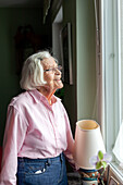 Ältere Frau blickt durch das Fenster