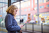 Woman using cell phone at bus stop
