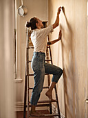Woman on ladder scraping wall