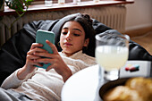 Girl lying on bean bag and using phone