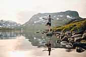 Frau beim Yoga an einem See in den Bergen