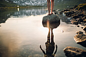 Tiefschnitt einer Person, die auf einem Felsen am See steht