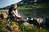 Frau sitzend an einem See in den Bergen