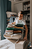 Woman holding basket with clothes, open wardrobe in background