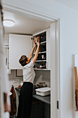 Woman putting basket into cupboard