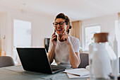 Smiling woman talking via cell phone at home