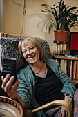 Ältere Frau benutzt Smartphone zu Hause