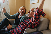 Älteres Paar sitzt auf dem Sofa und singt
