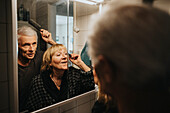 Senior couple brushing hair and doing make-up
