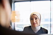 Frau mit Kopftuch im Café sitzend