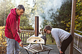 Man and woman using outdoor pizza oven