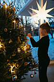 Junge beim Schmücken des Weihnachtsbaums zu Hause