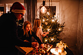 Father and daughters decorating Christmas tree