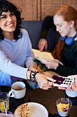 Young woman paying with card in cafe