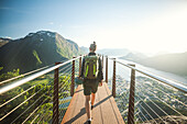 Rückansicht einer Wanderin auf einem Wanderweg über eine bergige Landschaft