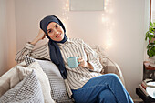 Woman on sofa using having coffee