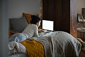 Mädchen macht Hausaufgaben mit Laptop in ihrem Schlafzimmer