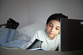 Mädchen macht Hausaufgaben mit Laptop in ihrem Schlafzimmer